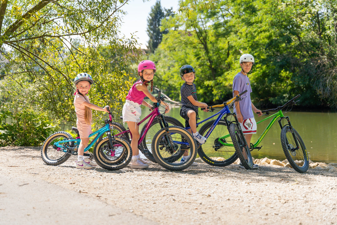 Vier Kinder mit Sqeeder Kinderfahrrädern in verschiedenen Größen – von 16 bis 26 Zoll